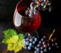 Un verre de vin rouge avec des grappes de raisin noir